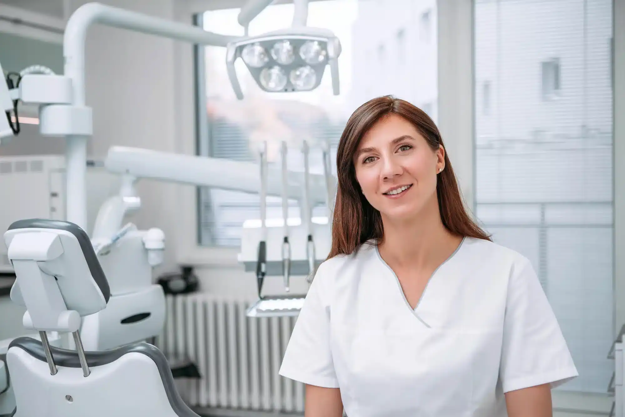 A female dentist in Downriver Detroit wearing white scrubs in dental office