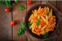 Piatto di penne con pomodorini e basilico fresco servito su tavolo rustico a Stigliano in Basilicata