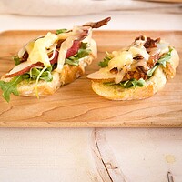 tartines topped with arugula, bacon, pears, dates, and cheese