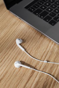 A modern desk setup with a laptop and white earphones on a wooden surface.