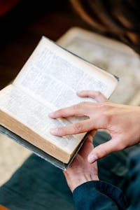 Close-up of hands holding an open religious book, creating a serene and contemplative mood.