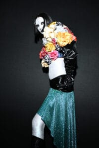 Side view of a high-fashion look from Esbolat Esmukhanov’s Almaty runway, showing long black satin gloves and a crop top composed of dozens of colorful decorative bows.