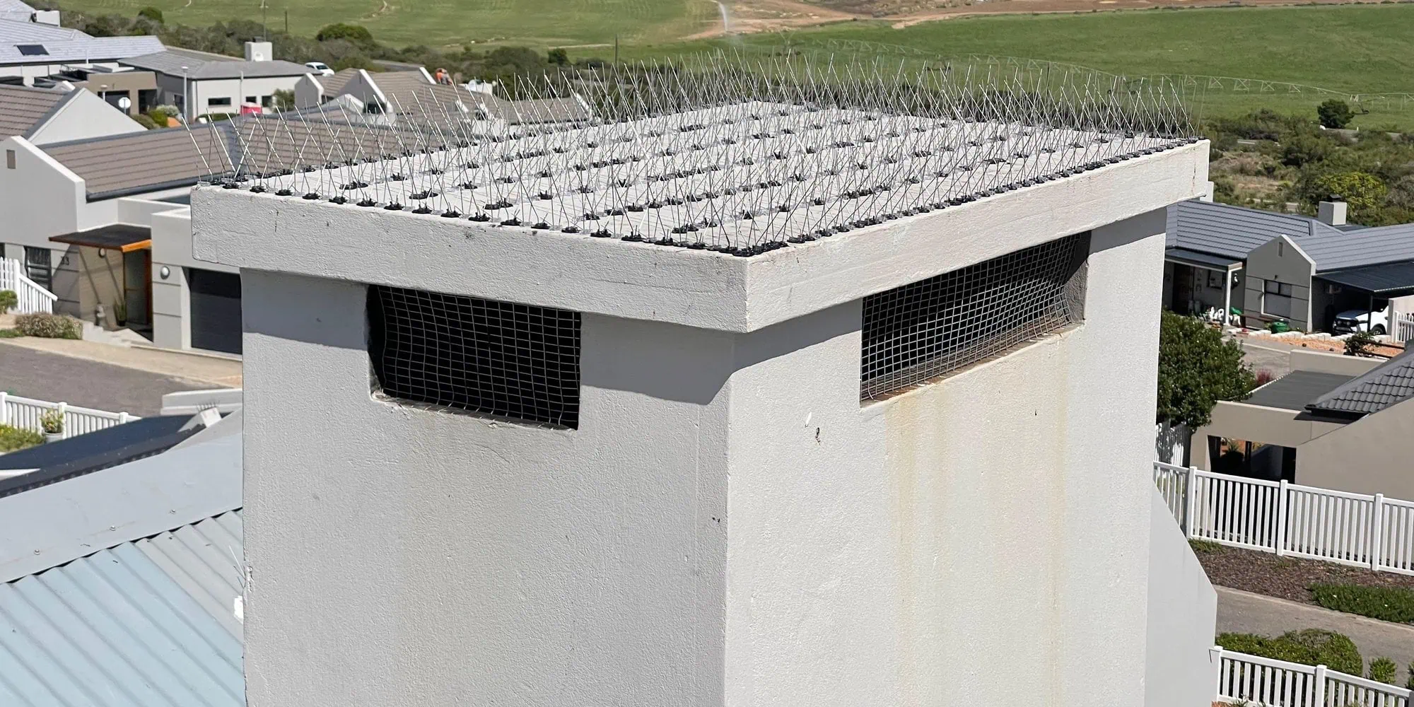 A proofed chimney on a Garden Route home, with mesh closing the openings and the estate and farmland behind.