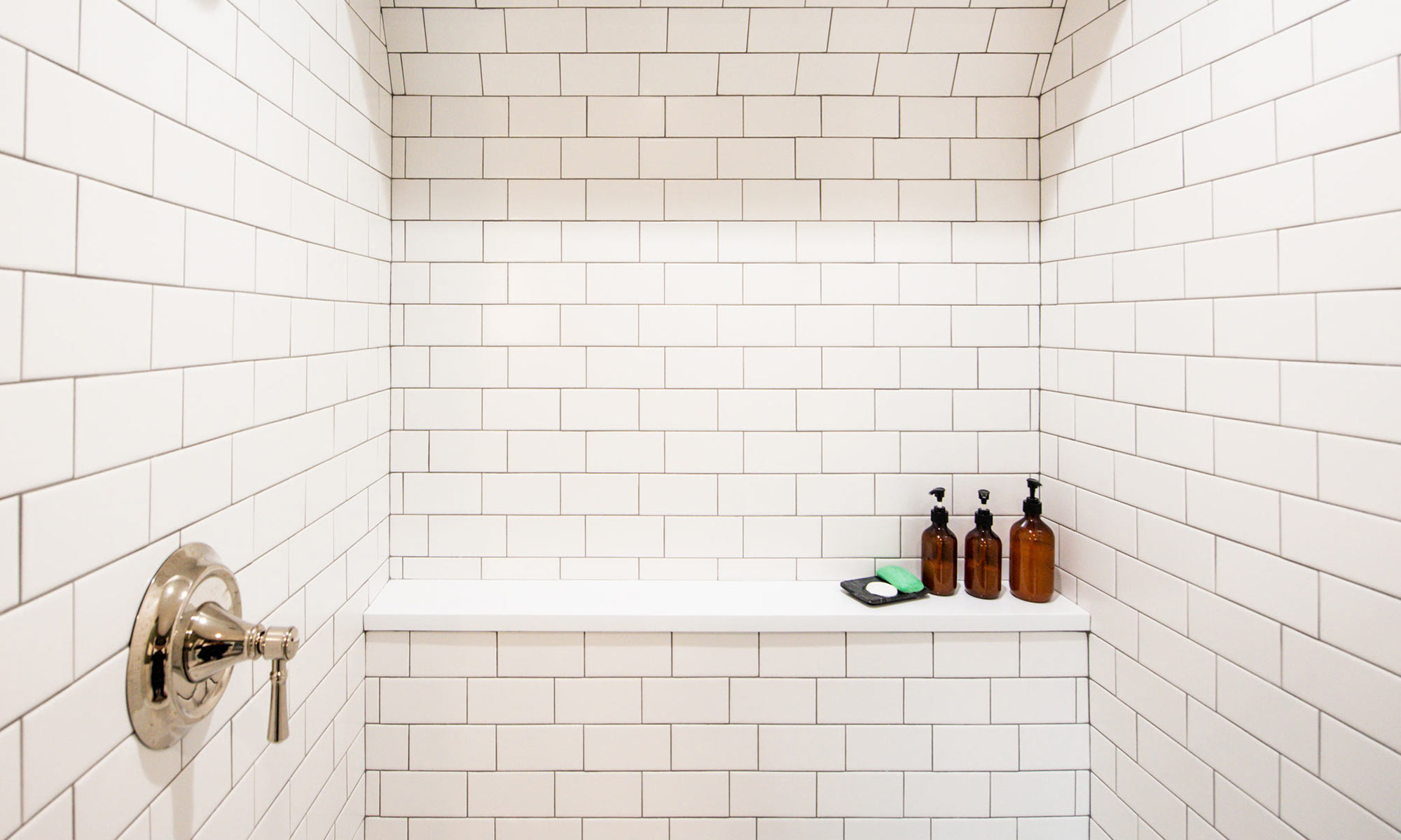 luxury shower with white subway tile and shampoo ledge