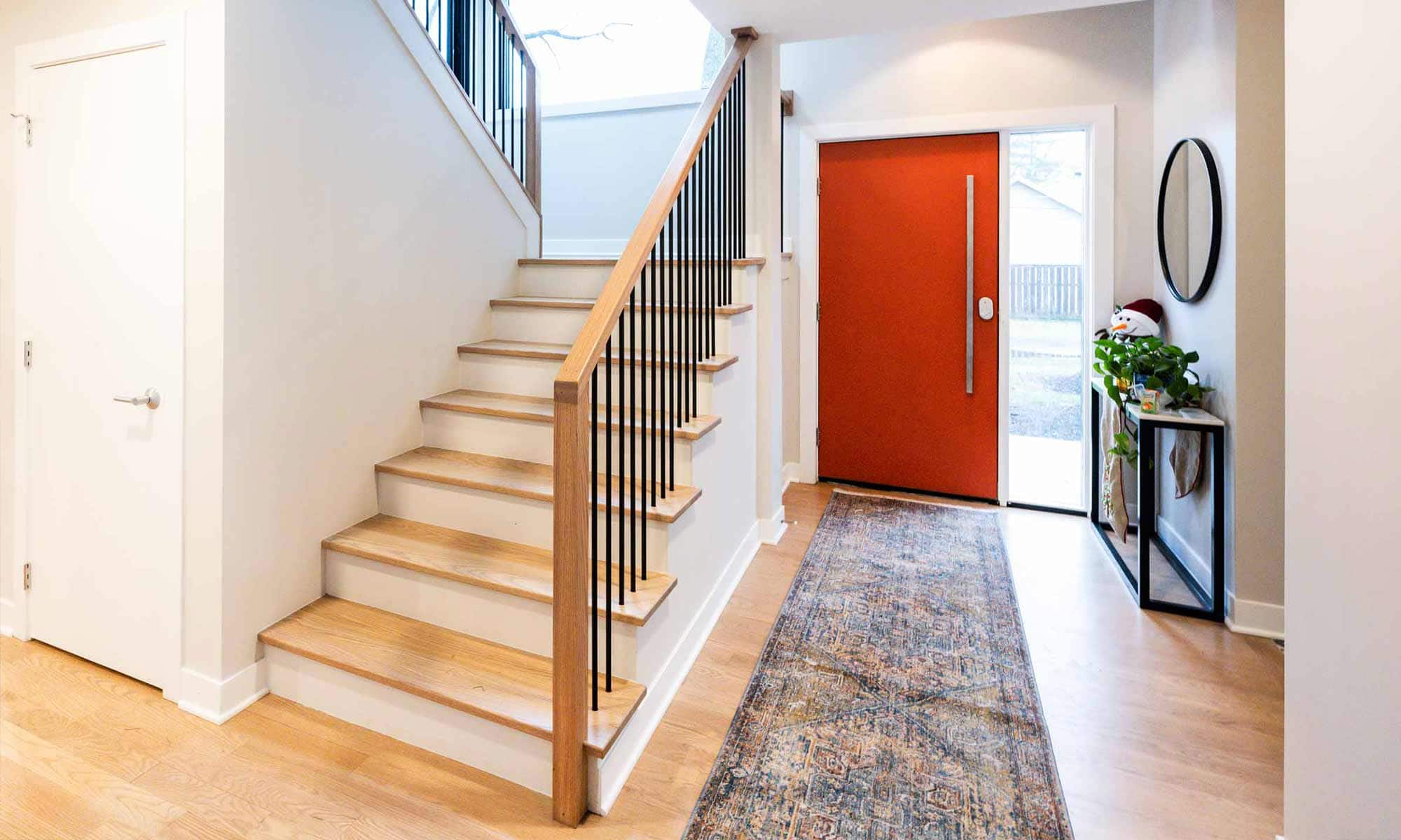 white oak stairway viewed from entrance hall in luxury second floor addition with modern orange front door