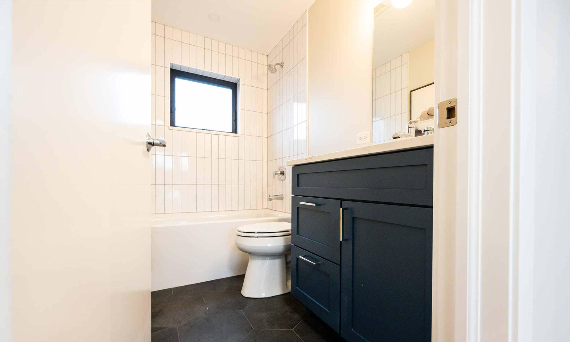 luxury bathroom remodel with grey floors and white shower tile and blue vanity