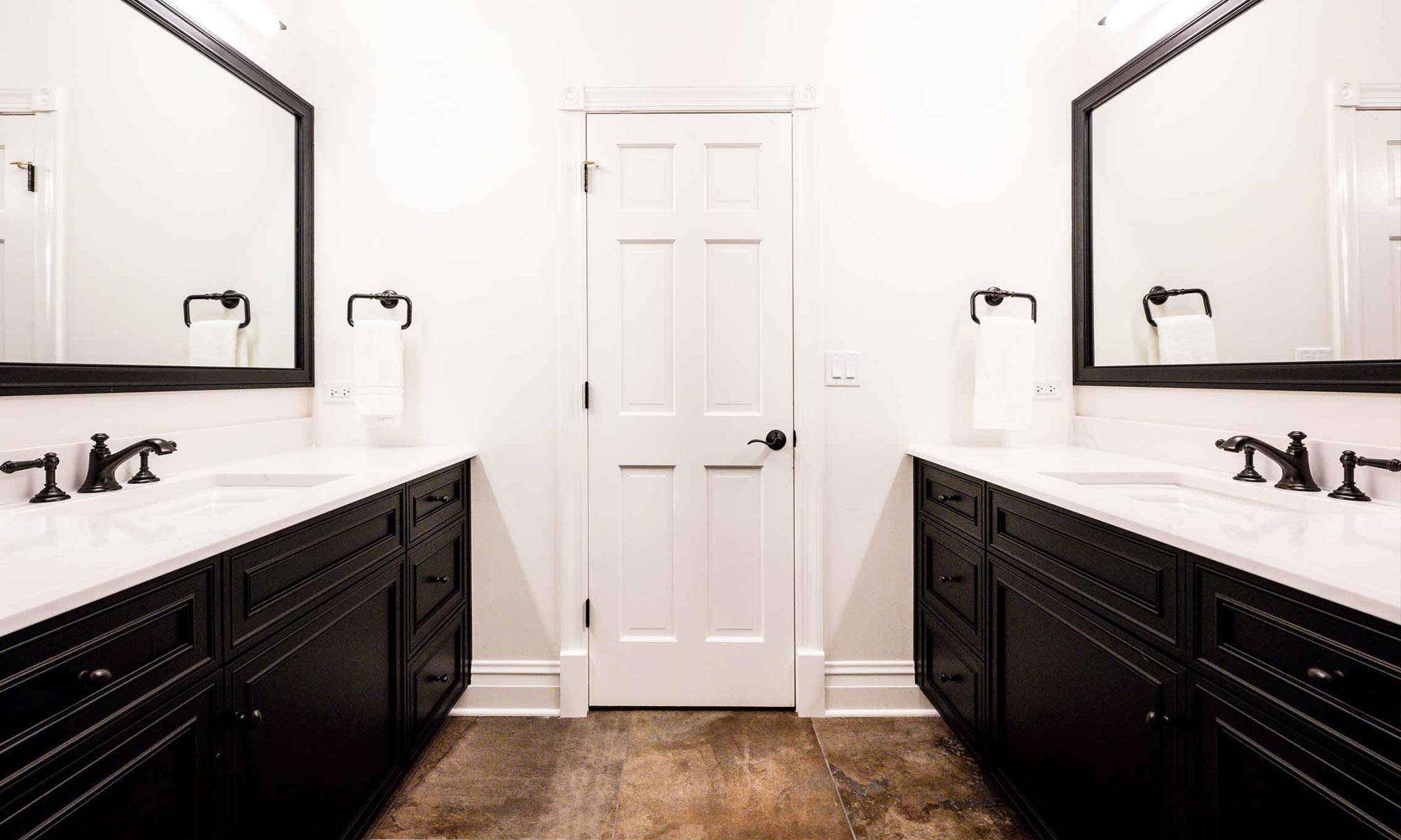 bathroom door flanked by vanities on both sides