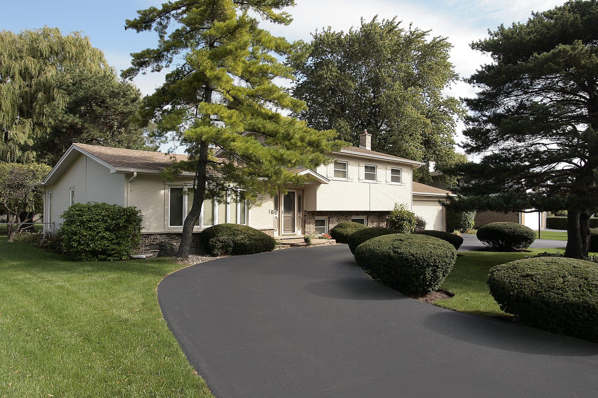 Tan home in suburbs with circular driveway