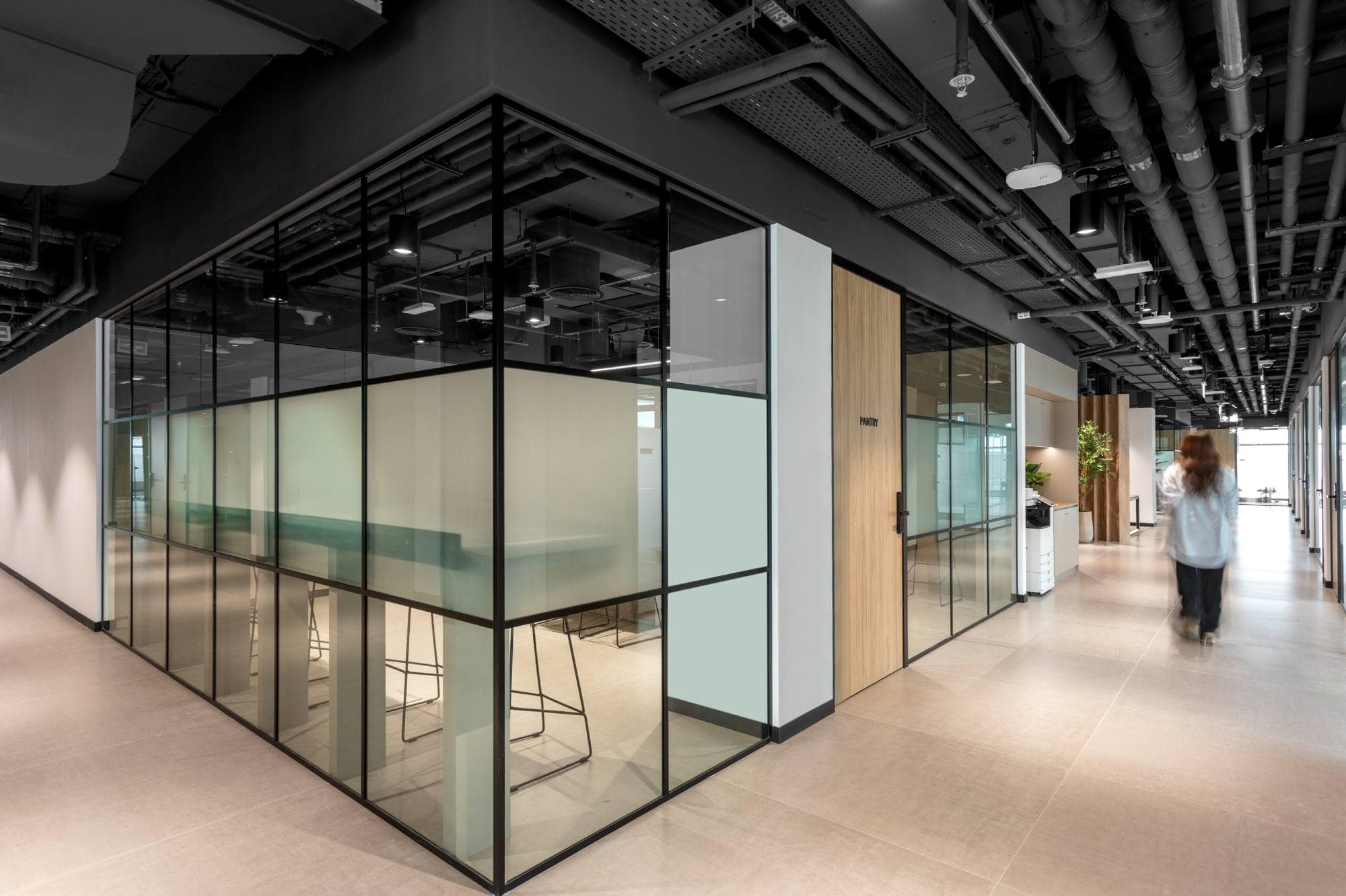 The sleek architectural design of Sentinel Dubai co-working space, highlighting frosted glass partitions, industrial-style ceilings, and clean walkways that define a premium professional environment.