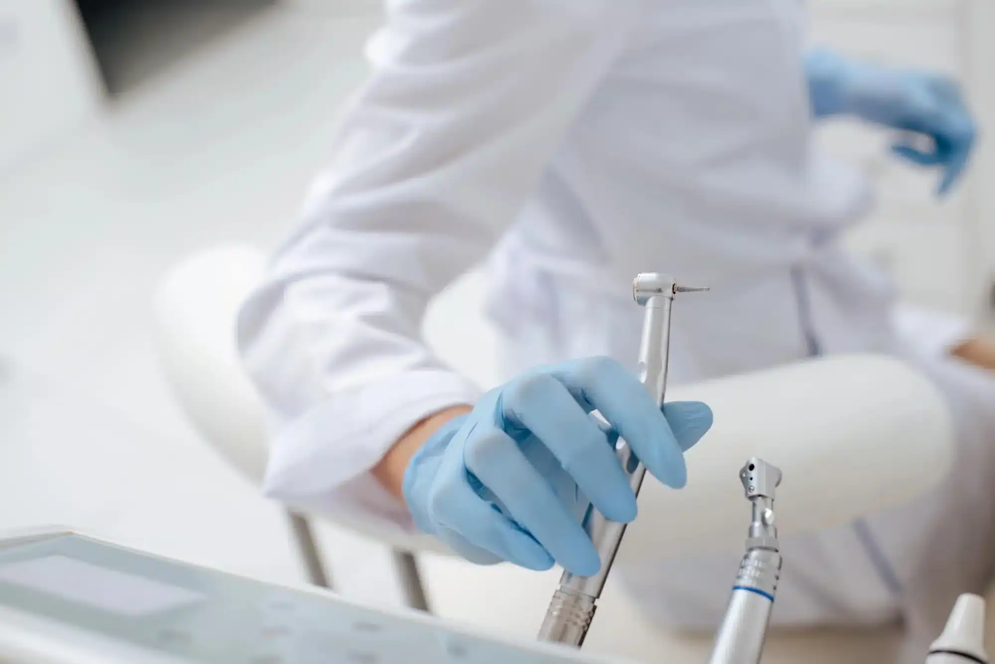 Unrecognized dentist in Downriver Detroit holding instrument in room