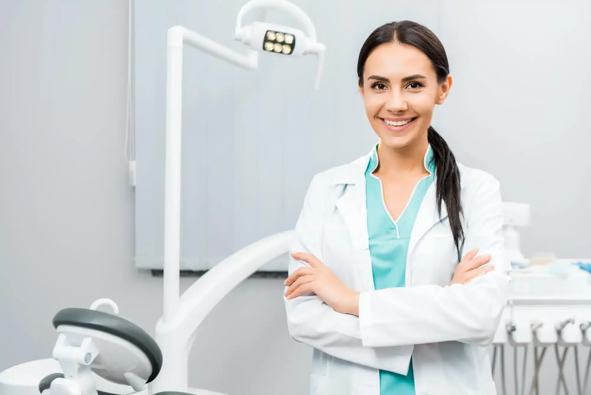 Young female and smiling dentist in Downriver Detroit standing with arms crossed
