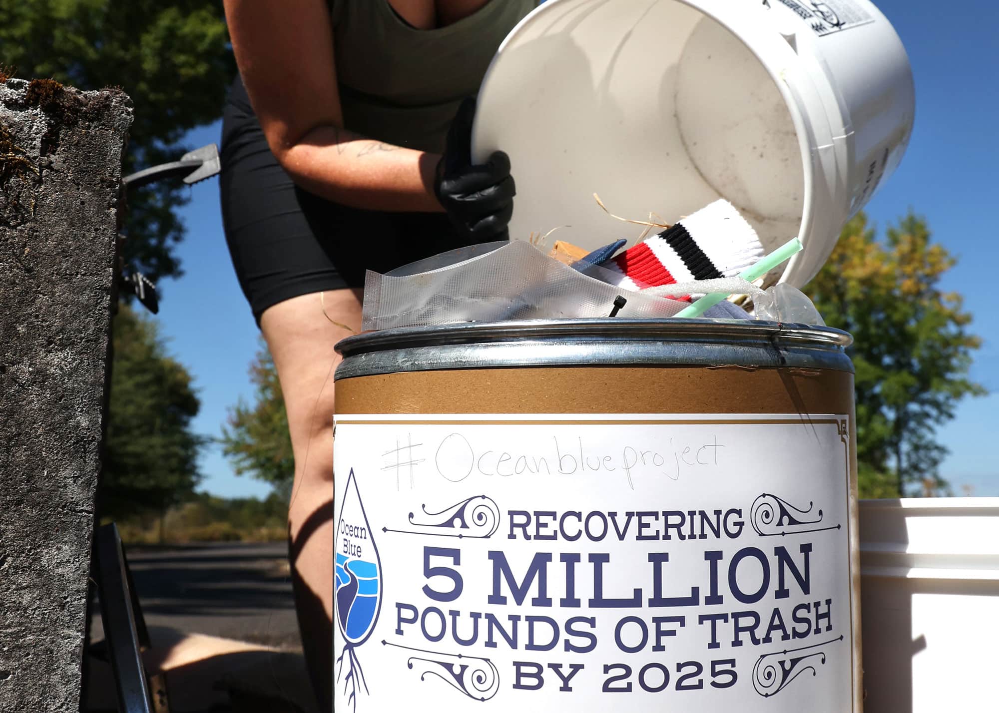 Volunteer emptying a bucket of debris into a receptacle.