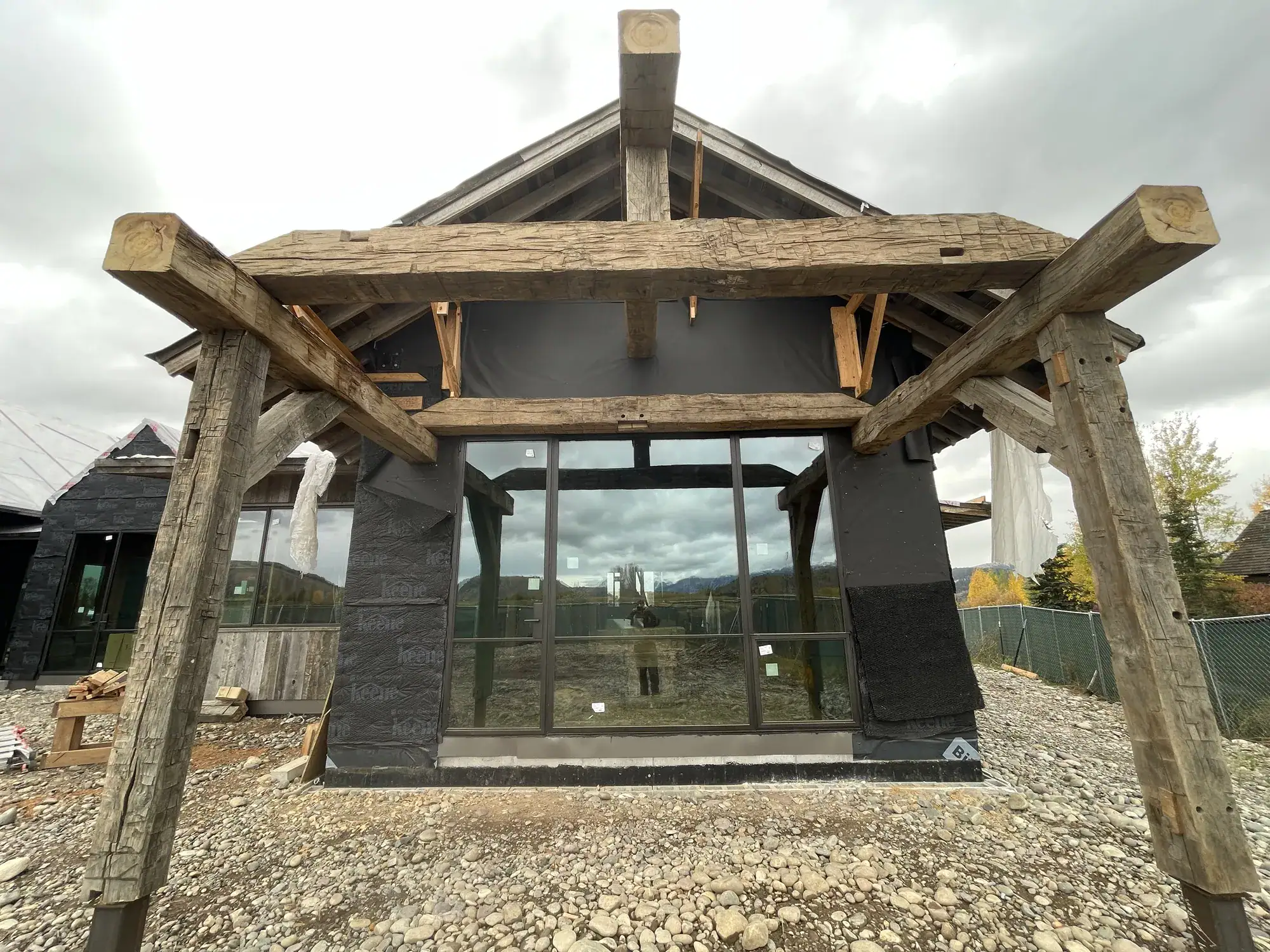 Hand-hewn timber entry truss on round log posts at a residence under construction