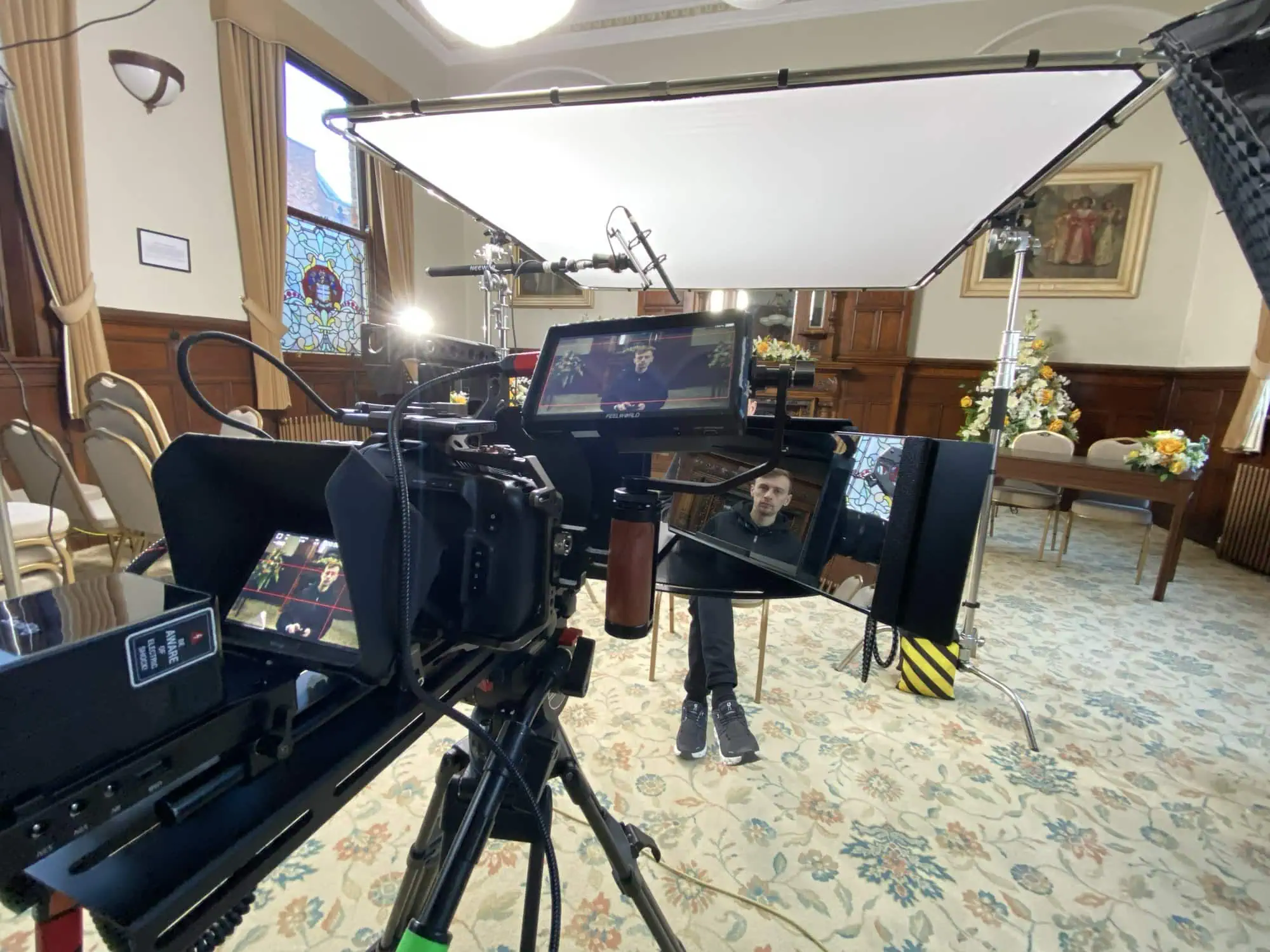 Interview lit and rigged in a panelled room, two cameras and a large diffuser overhead