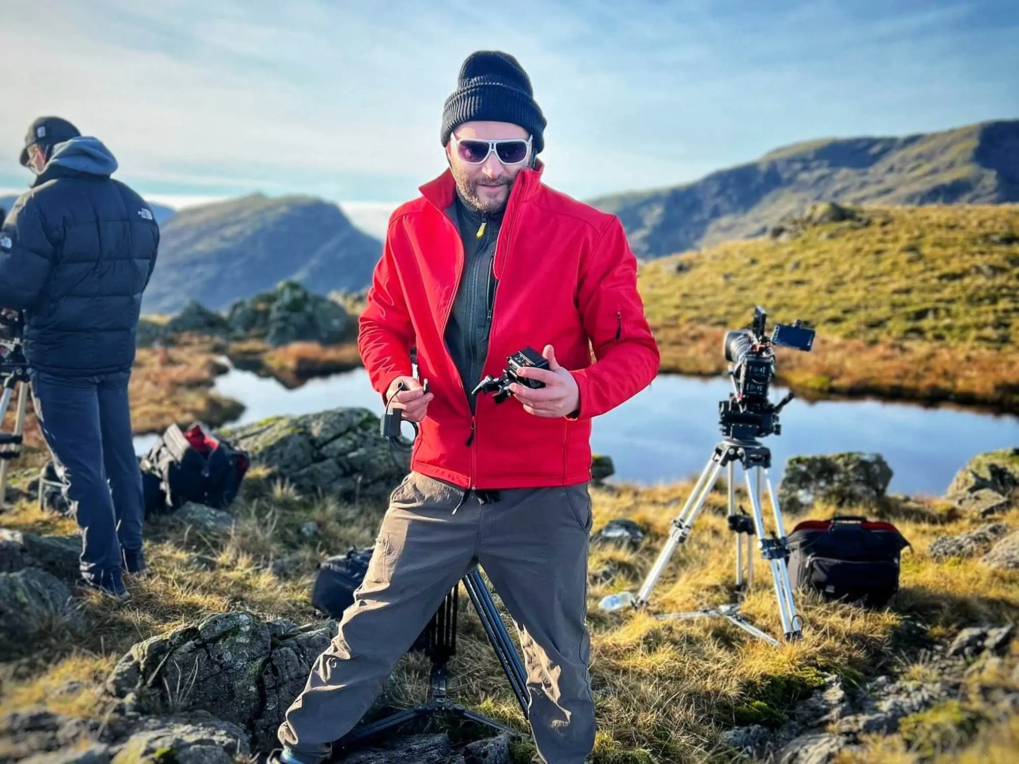 Aposs crew setting up a camera beside a lake on a hillside shoot