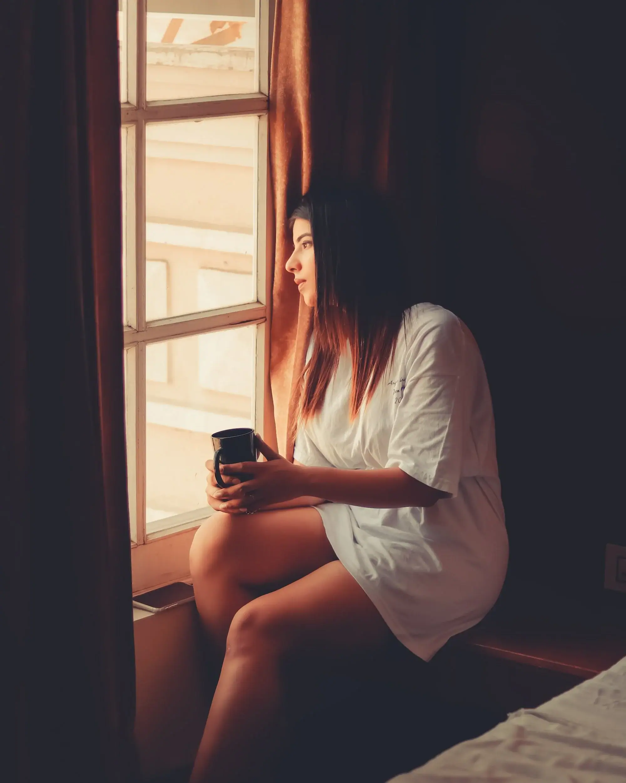 woman staring out the window with tea. Begin Anxiety treatment in Detroit now.