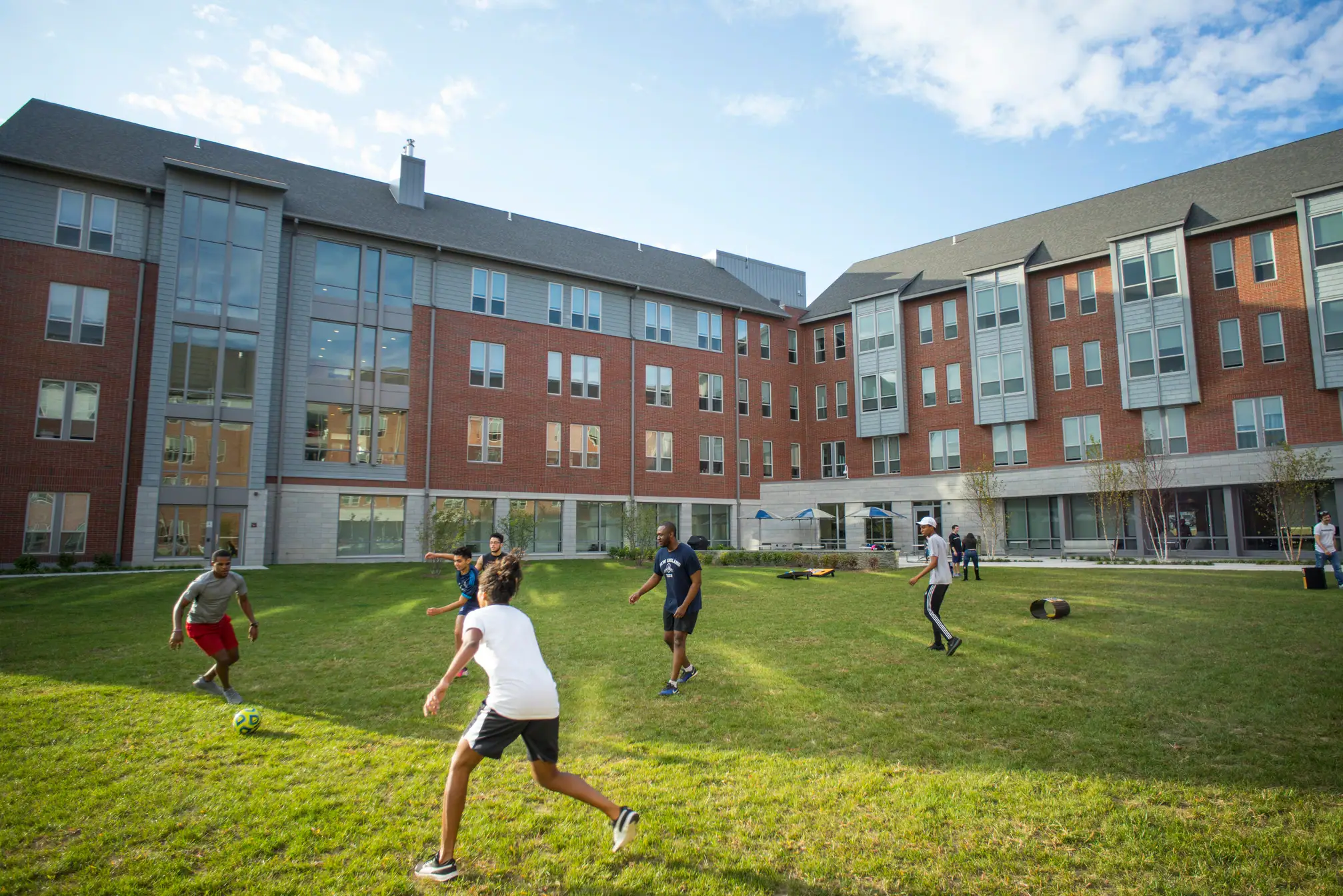 Photo of people playing soccer on a field on a school campus