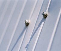 Detailed view of metal screws securing a steel sheet, highlighting the durability of materials for Ontario home addition