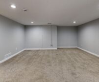 Open basement room with neutral gray walls and plush carpeting, ready for a complete Waterloo basement remodeling transf