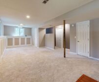 Bright, modern finished basement with plush carpet flooring and recessed lighting, showcasing an open-concept layout aft