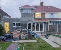 Home Addition cost in Kitchener - A suburban house undergoing major renovations with scaffolding and building materials.