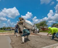 Concrete workers pouring a new driveway in Fort Worth, TX under a bright blue sky, for Kitchener home ROI guide.
