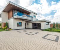Modern home exterior with lush landscaping and wide concrete driveway, ideal for a 2000 sq ft summer installation in Kit