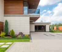 Spacious concrete driveway at a modern minimalist home in Hamilton, Ontario, with landscaped garden and clear blue sky.
