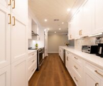 Kitchen Renovation cost in Cambridge - Bright modern kitchen with white cabinets, wooden floor, and appliances.