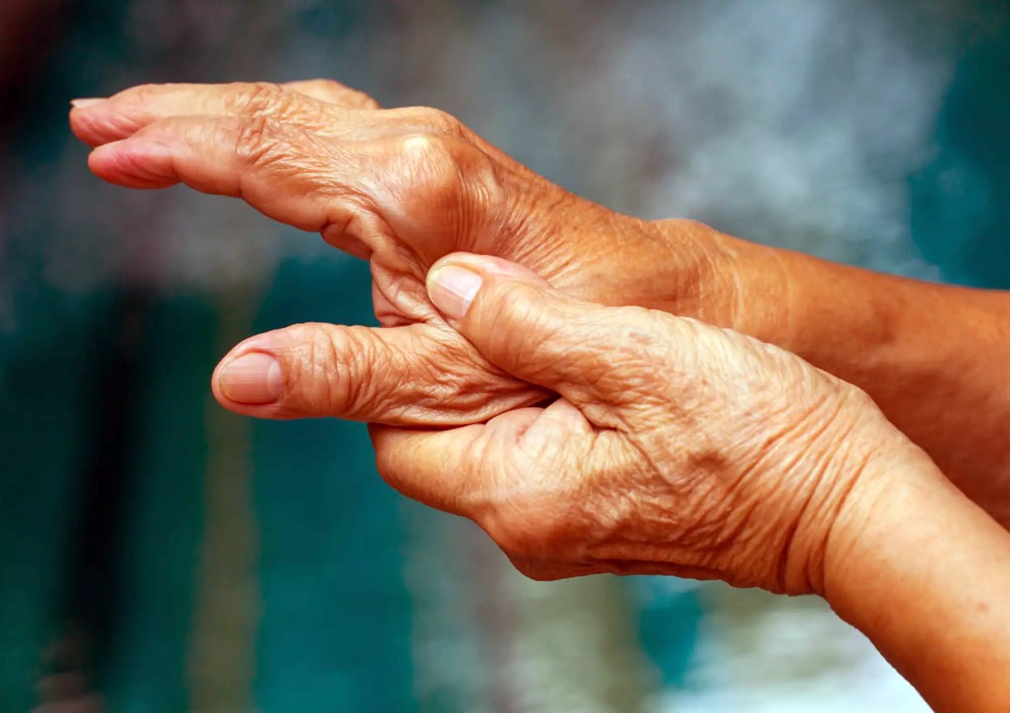 Elderly person gently holding their own hand, symbolizing chronic pain, self-comfort, and autoimmune disease management at BionwoRx in Carmel, Indiana
