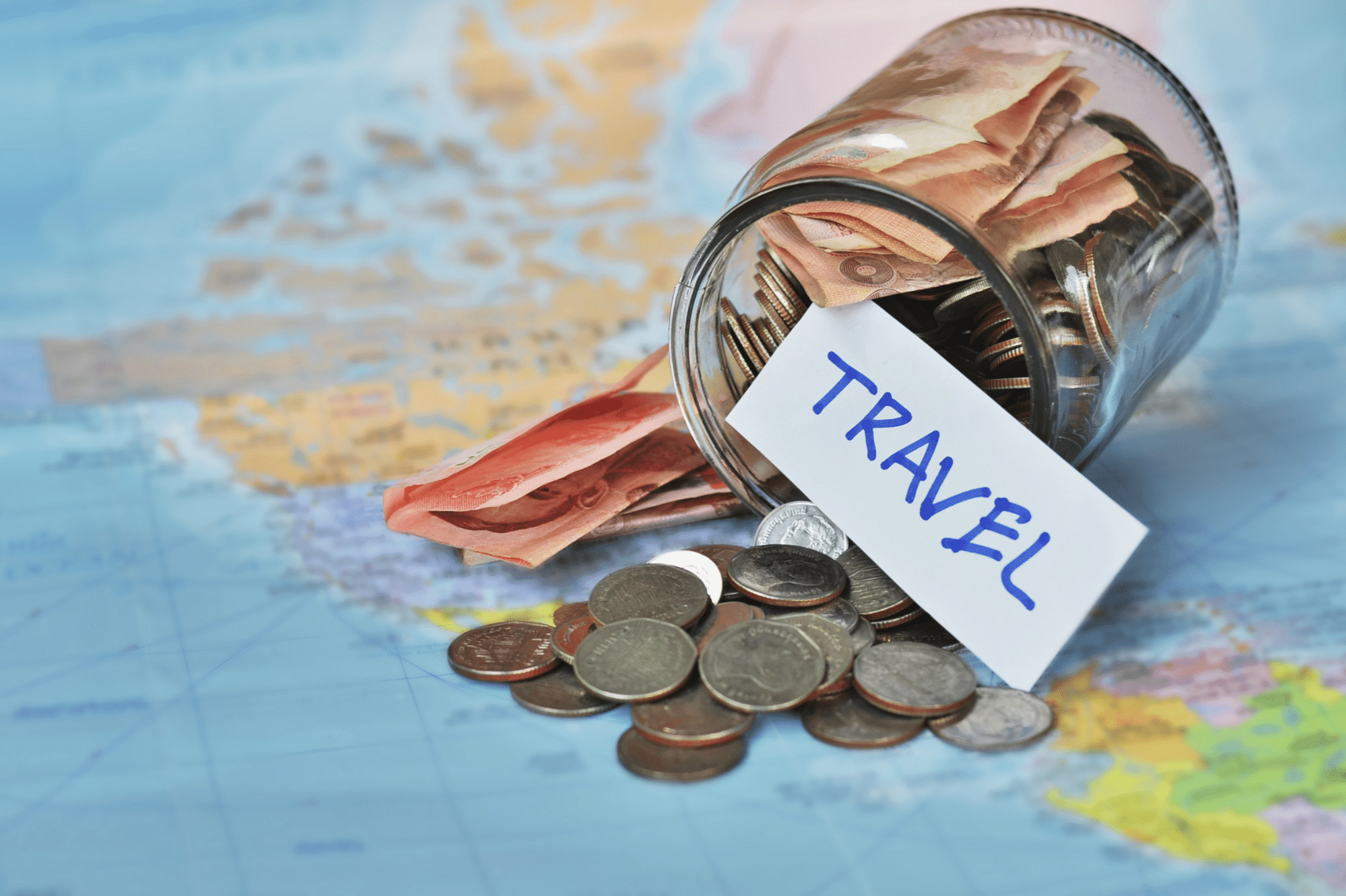 a world map with money from a budget jar spilled over with a stickers saying "travel"