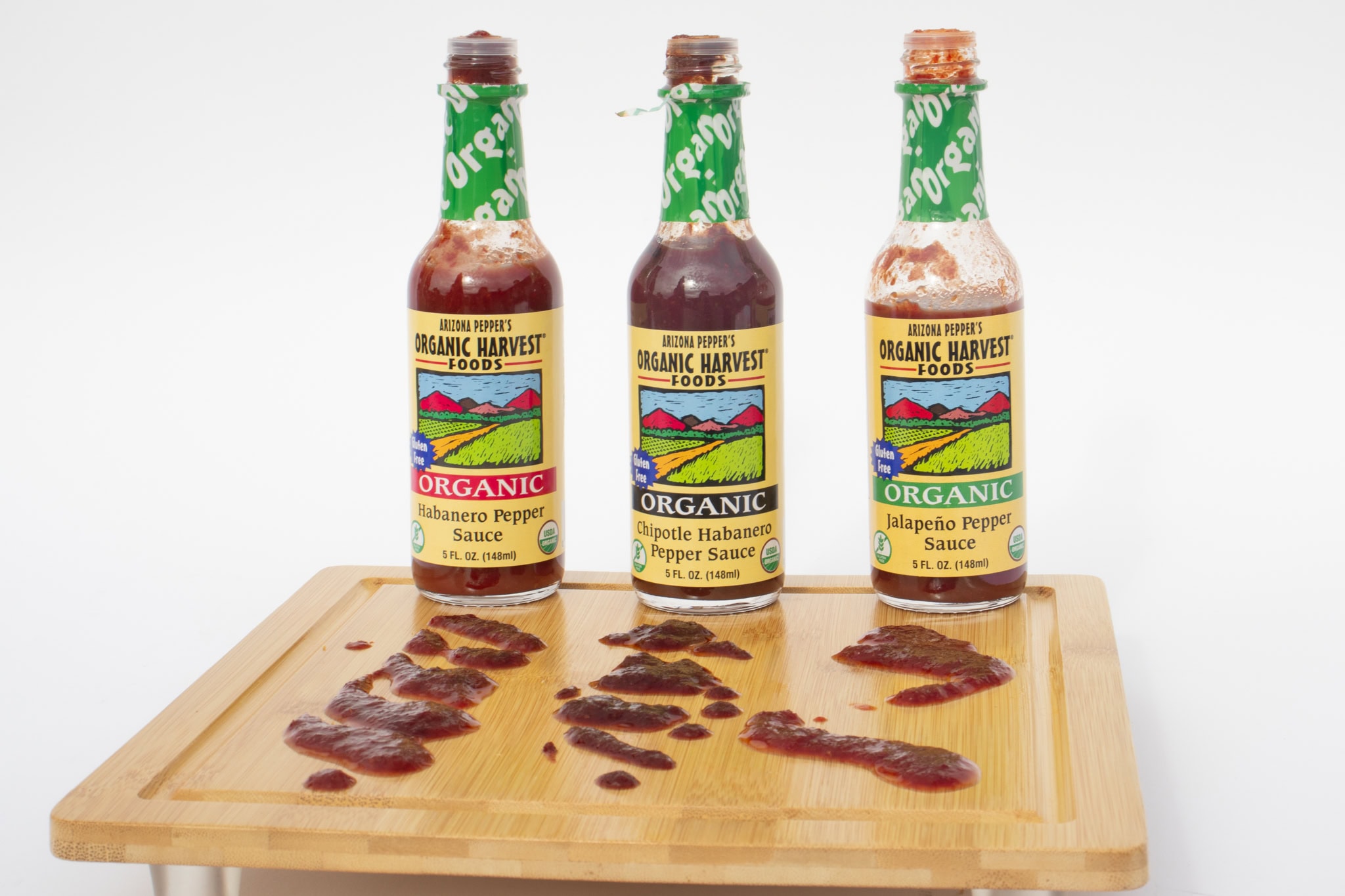 Bottles of signature Arizona Pepper Products sauces lined up on a rustic table.