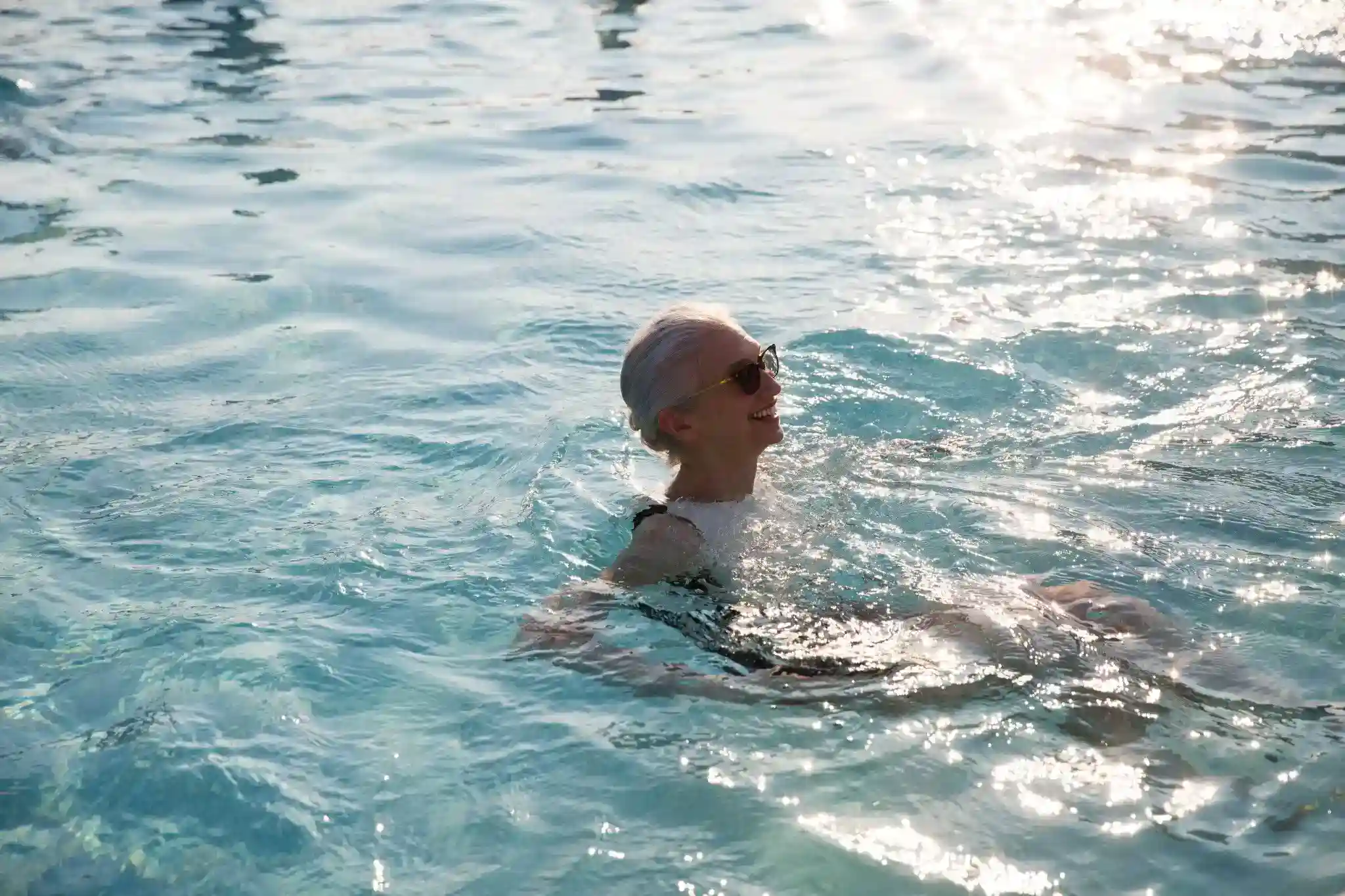 Resident enjoying a luxury outdoor swimming pool with sparkling water on a sunny day.
