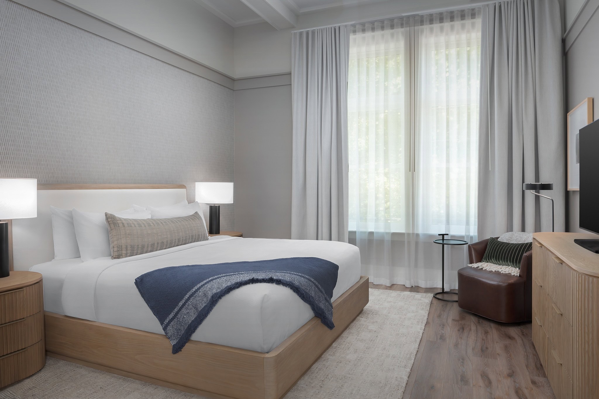 Wide view of Heritage Room with king bed, tall windows, and contemporary lounge chair.