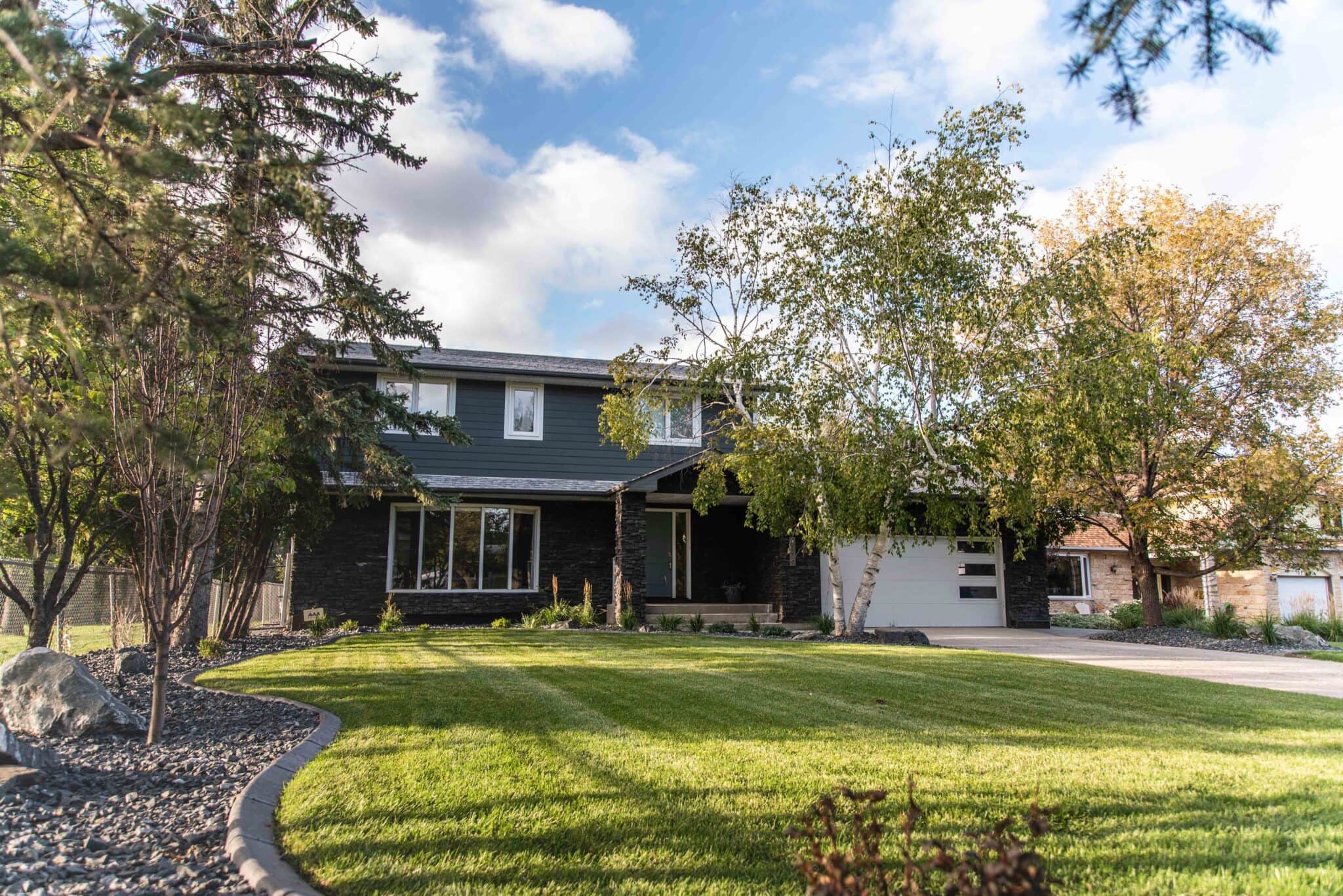 Completed home landscape with green lawn and trees.