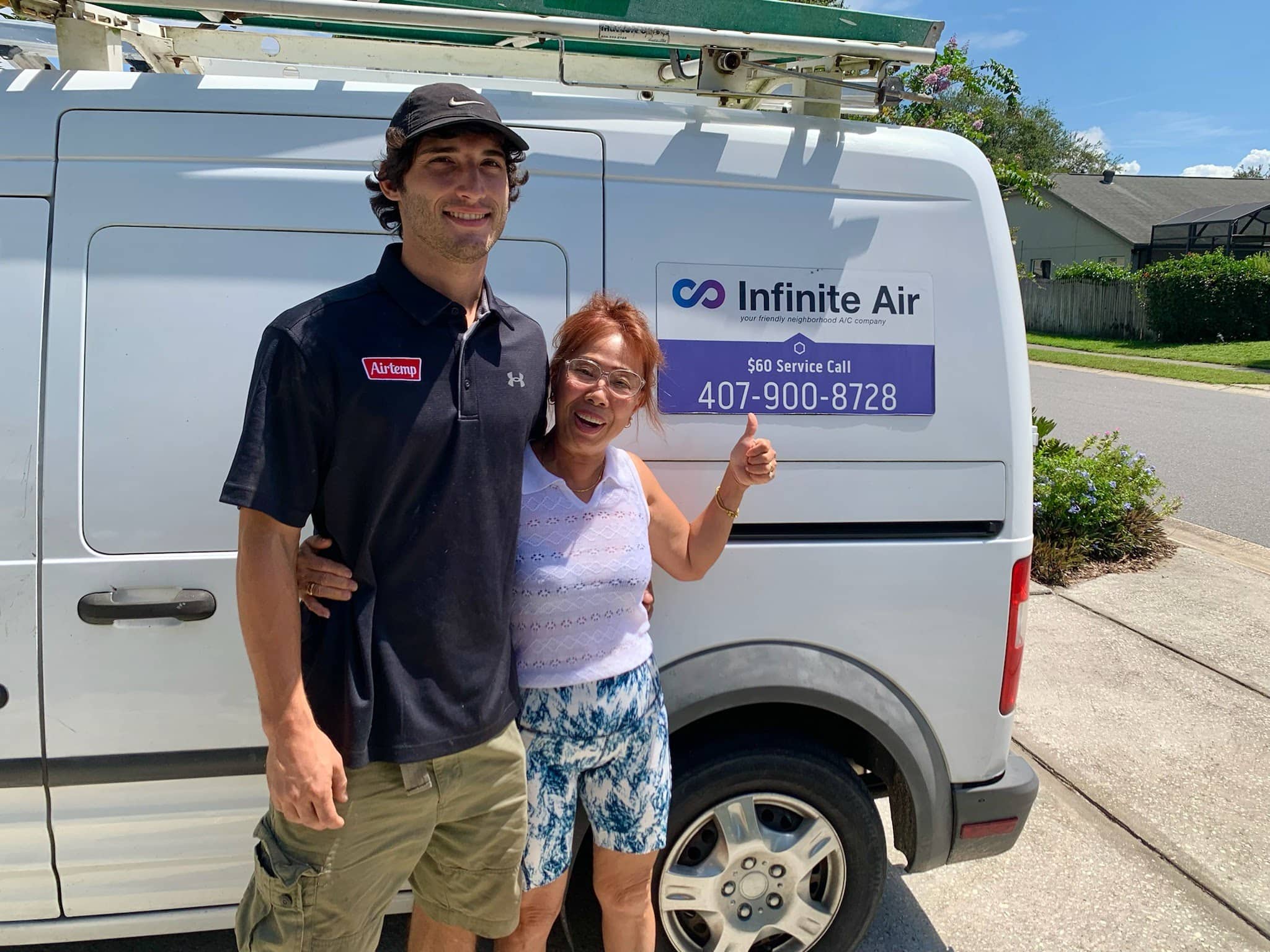 Image of a AC tech and a customer standing in front of a work van.
