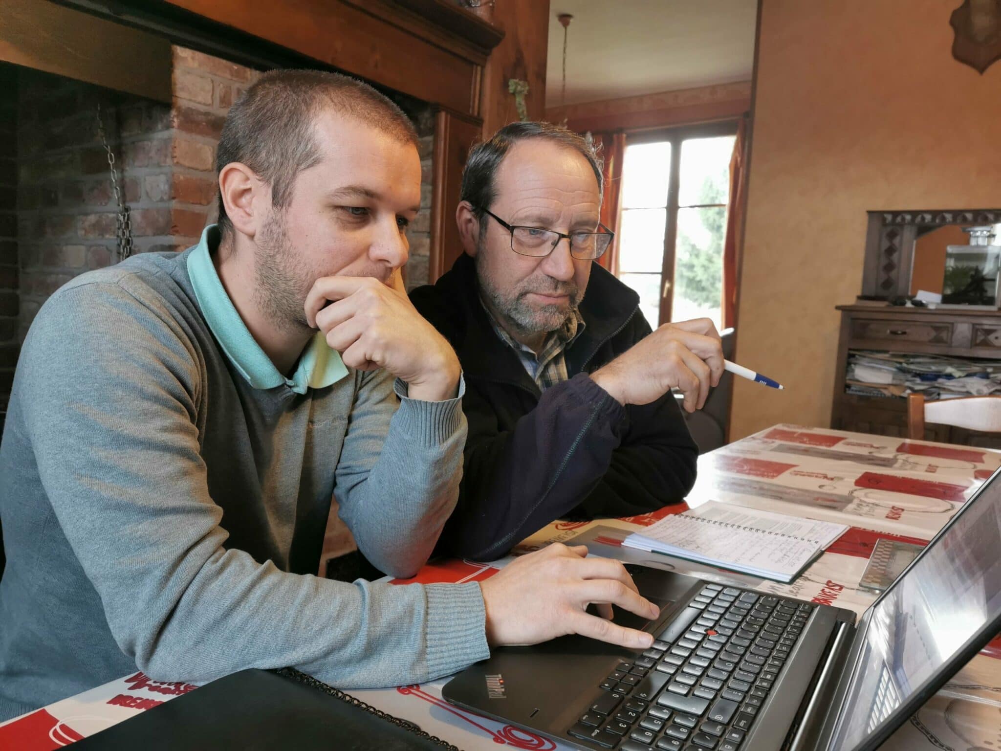 Un technicien et un agriculteur devant un ordinateur pilotant l'exploitation