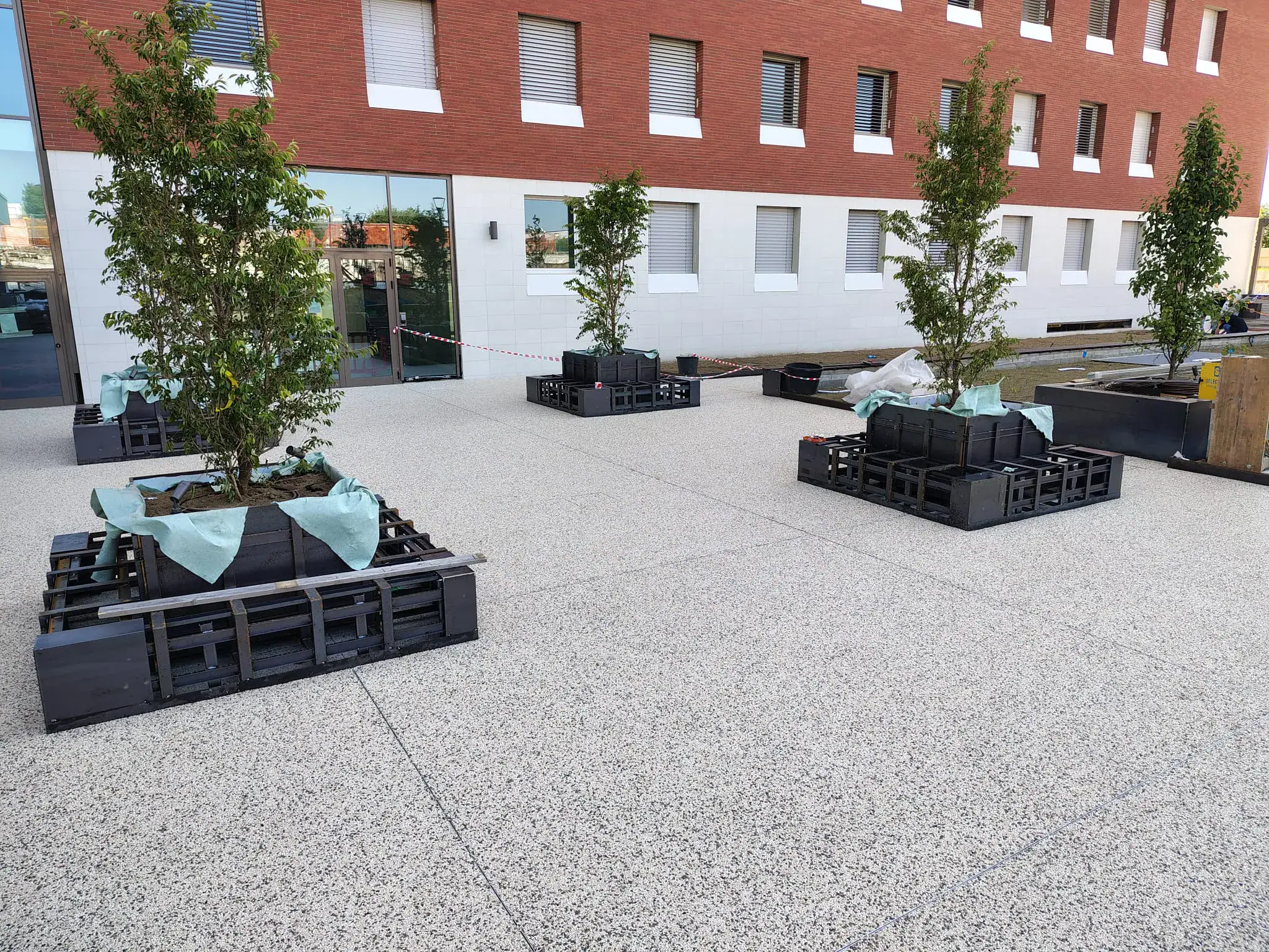 Pavimentazione drenante Prima Drain Stone® posata nell'area esterna dello student housing di Bovisa, Milano. Superficie in aggregato di pietra legato con resina poliuretanica trasparente, effetto ghiaia stabilizzata, integrata nel contesto urbano residenziale del campus universitario.