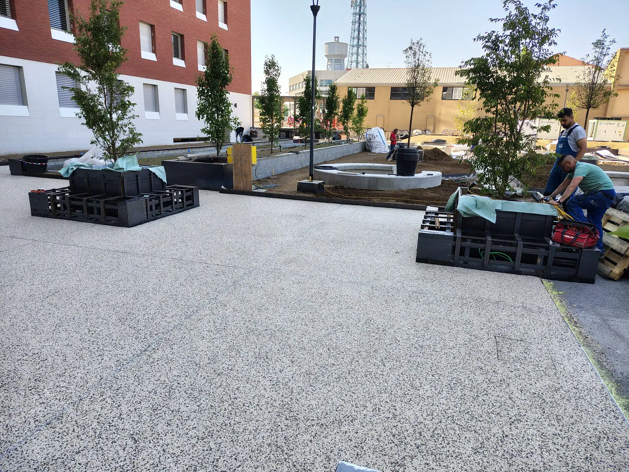 Pavimentazione drenante Prima Drain Stone® posata nell'area esterna dello student housing di Bovisa, Milano. Superficie in aggregato di pietra legato con resina poliuretanica trasparente, effetto ghiaia stabilizzata, integrata nel contesto urbano residenziale del campus universitario.
