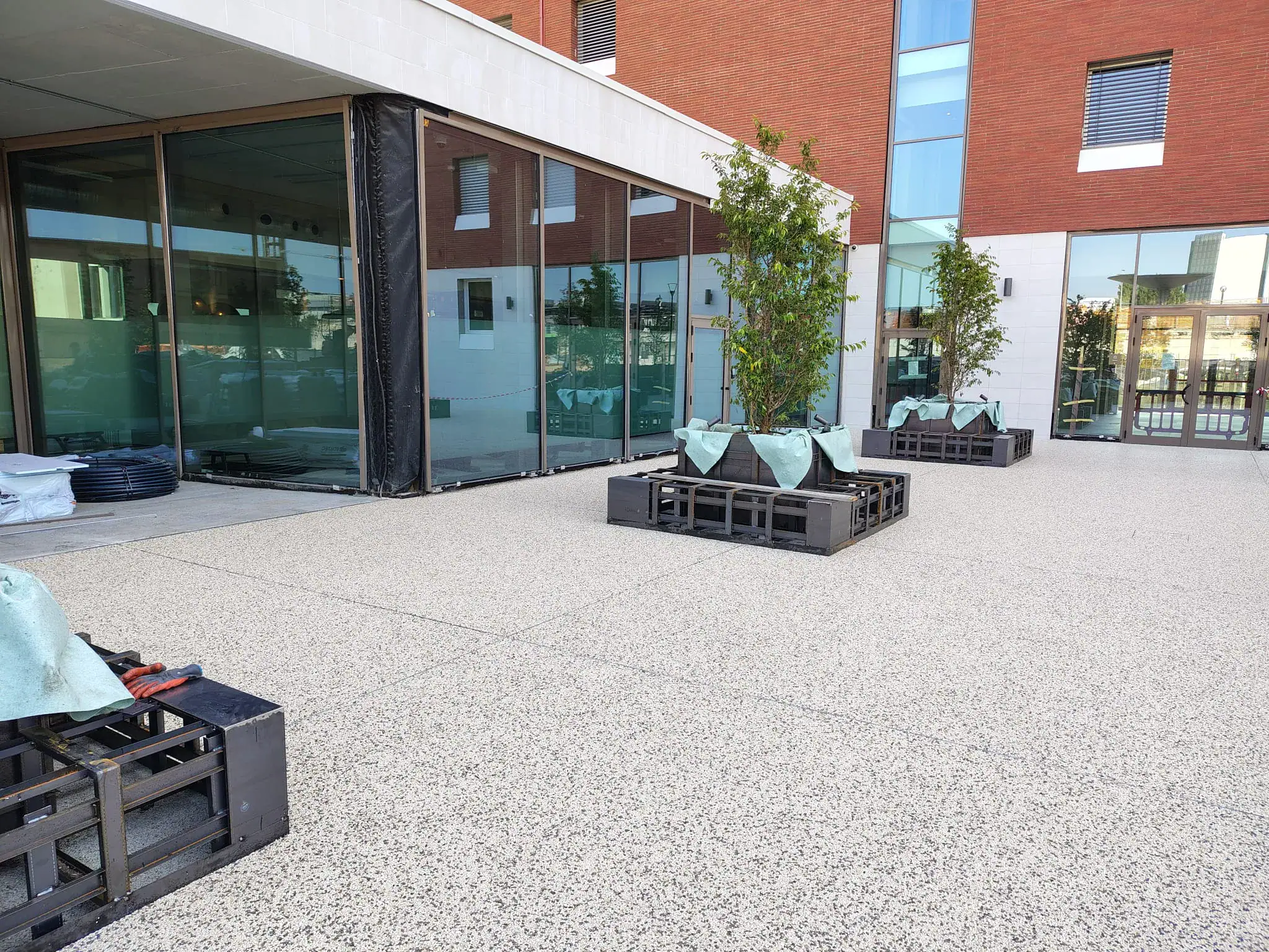Pavimentazione drenante Prima Drain Stone® posata nell'area esterna dello student housing di Bovisa, Milano. Superficie in aggregato di pietra legato con resina poliuretanica trasparente, effetto ghiaia stabilizzata, integrata nel contesto urbano residenziale del campus universitario.