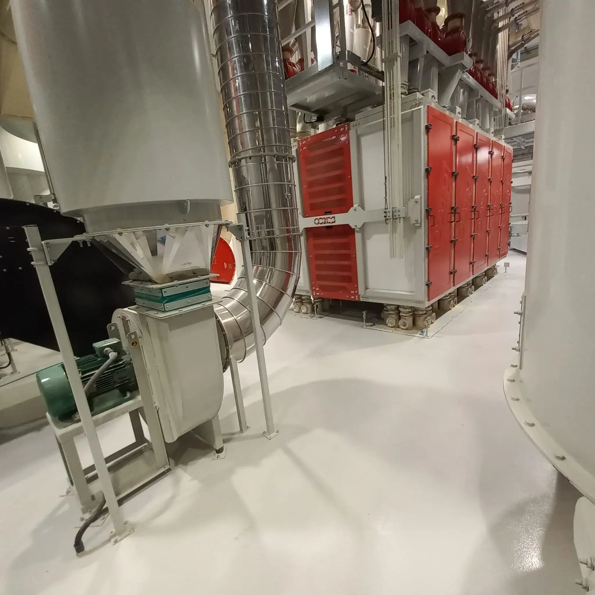 Pavimento in resina per mulino industriale: vista del piano di produzione con impianti di macinazione cereali e superficie continua resistente all'usura
