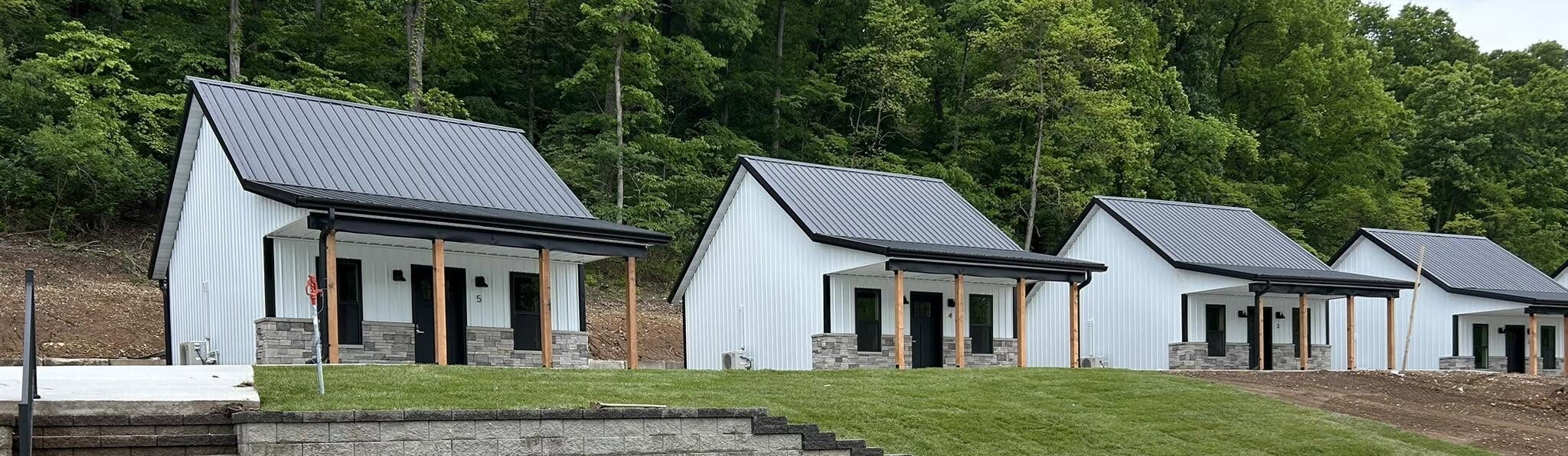 Row of white on-site wedding cottages with metal roofs at Romaine Valley Weddings & Events in Fenton, Missouri