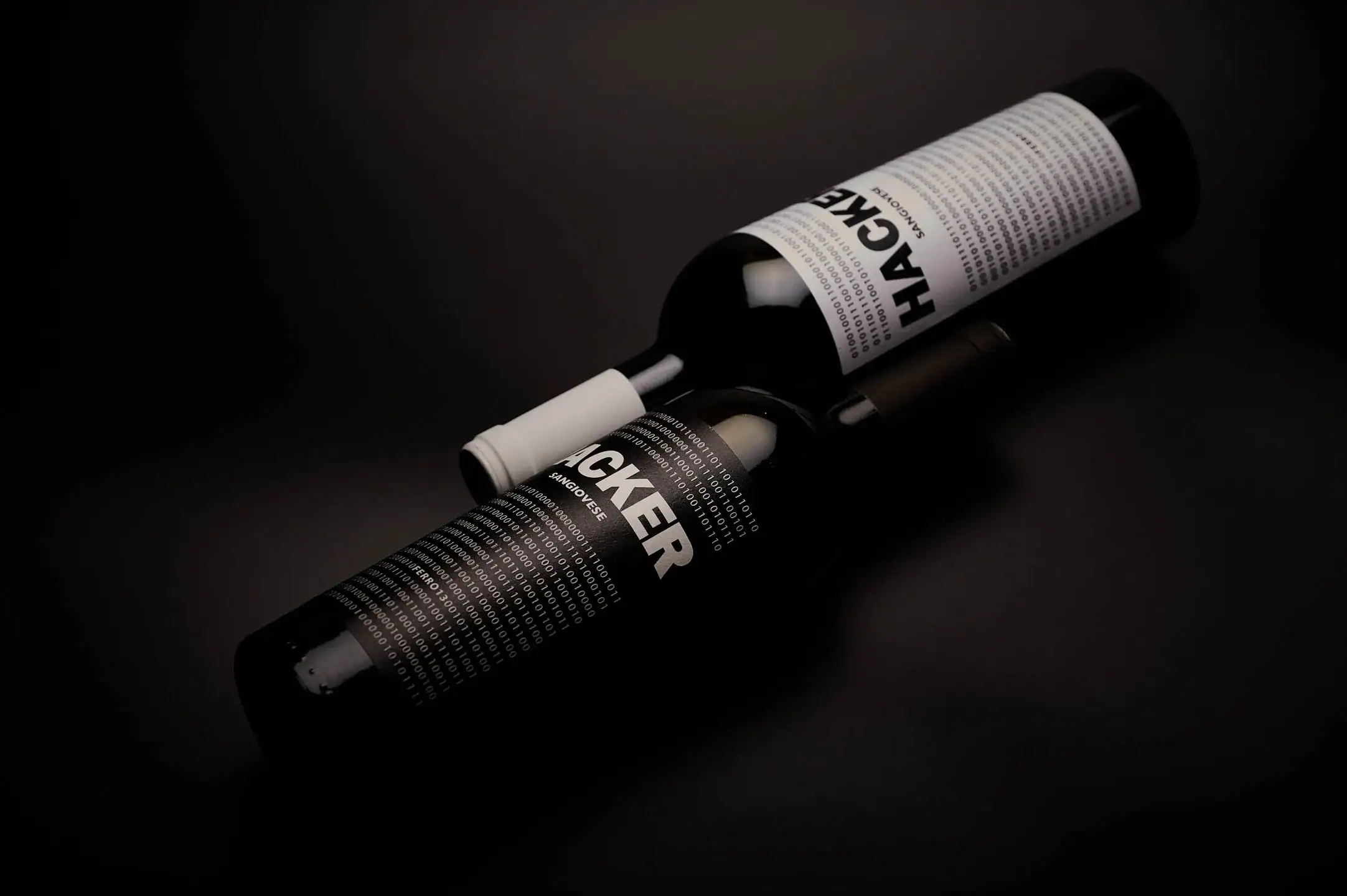 Bottiglia di Sangiovese "Hacker" della cantina Ferro13, disponibile in due colorazioni qui affiancate su uno sfondo nero
