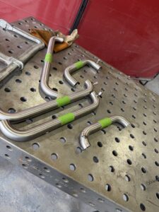 Inconel tube bends fitted with argon purge plugs, fixtured on a welding table for precision TIG welding