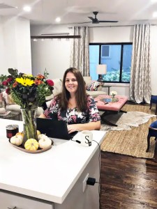 Vase of colorful flowers on a white desk inside a cozy, well-decorated living room setting for Soulstice Living.