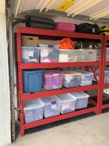 Storage shelving with organized plastic bin containers in a garage or storage area.