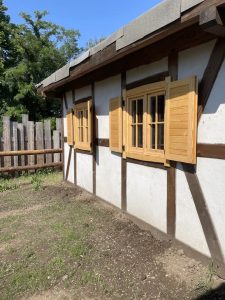 Hüttenfassade mit traditionellen Holzfenstern und Fenstergittern, umgeben von Natur und Garten. Perfekt für einen erholsamen Aufenthalt im Wellnesshof RaJa.