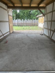 Betonboden in einer Wellnesshof-RaJa-Holzhütte, Blick nach draußen auf grünen Garten, Handwerksarbeit, Baufortschritt, Erholung im Grünen, naturnaher Wellnessbereich, nachhaltige Bauweise, Ruhe und Entspannung.