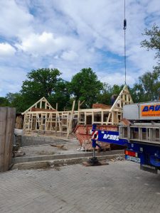 Holzrahmenbau im Bauprojekt auf dem Wellnesshof RaJa, aktive Bauarbeiten für ein nachhaltiges Wellness- und Urlaubsdomizil, Handwerker beim Errichten des Dachstuhls, Bauarbeiten im Grünen.