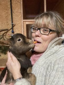 Spielende Frau mit Babyziege, Tierliebe, Tiertherapie, Entspannung, Tiergestützte Aktivitäten, Wellnesshof RaJa, Bauernhof Erlebnis, Natur und Tierkontakt, tiergestützte Therapie, Tierliebe in Deutschland.